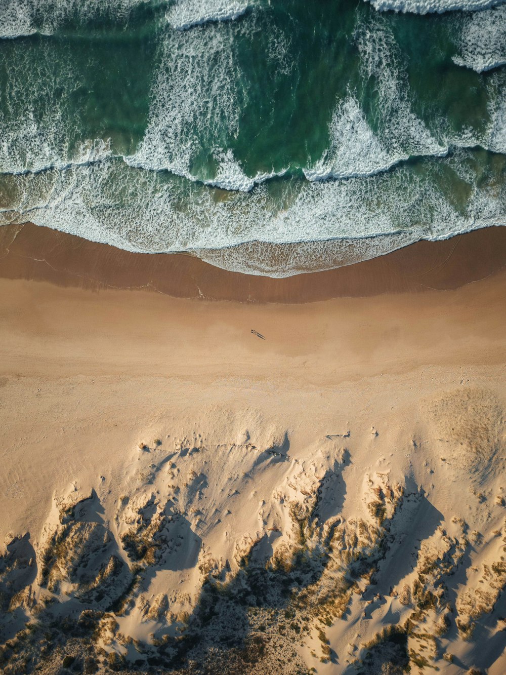 uma vista aérea de uma praia de areia e oceano