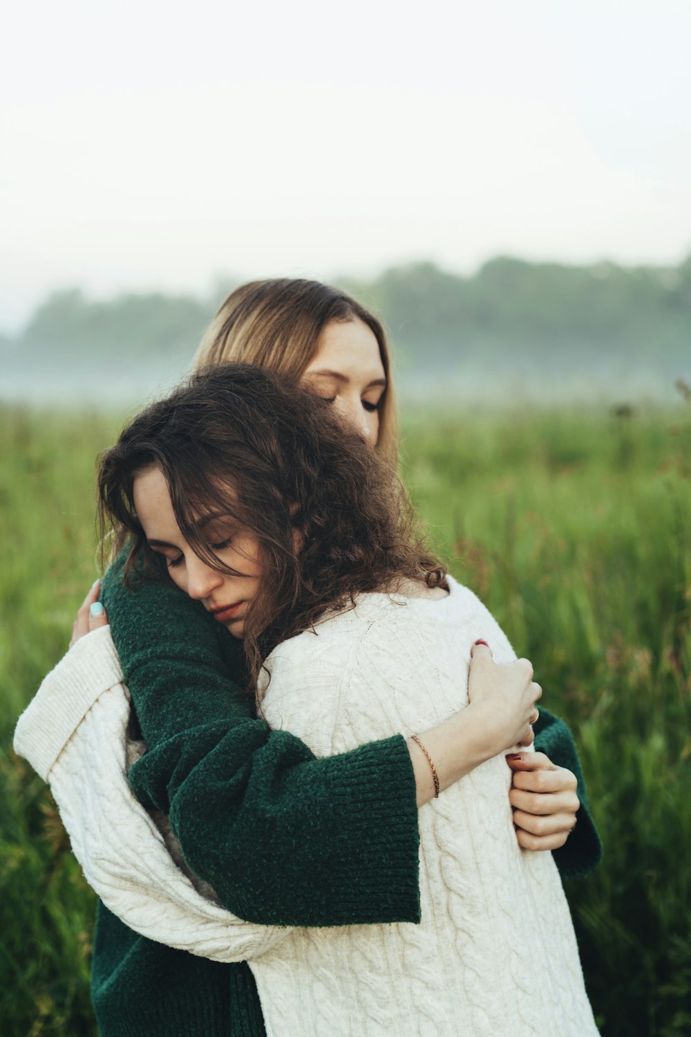 two women hugging in a field of tall grass