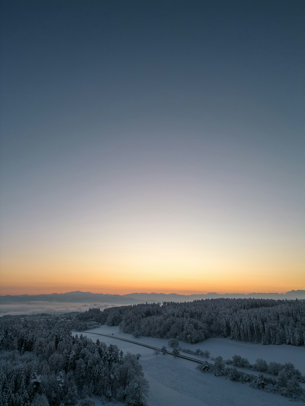 the sun is setting over a snowy landscape