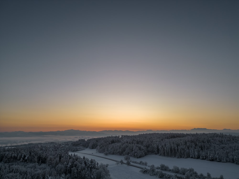 the sun is setting over a snowy landscape