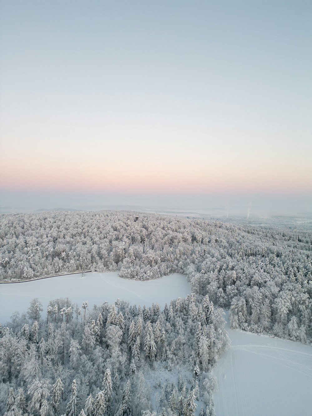 an aerial view of snow covered trees and a lake