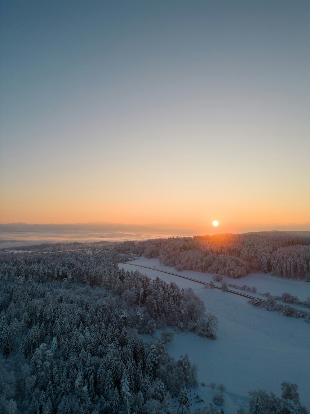 the sun is setting over a snowy landscape