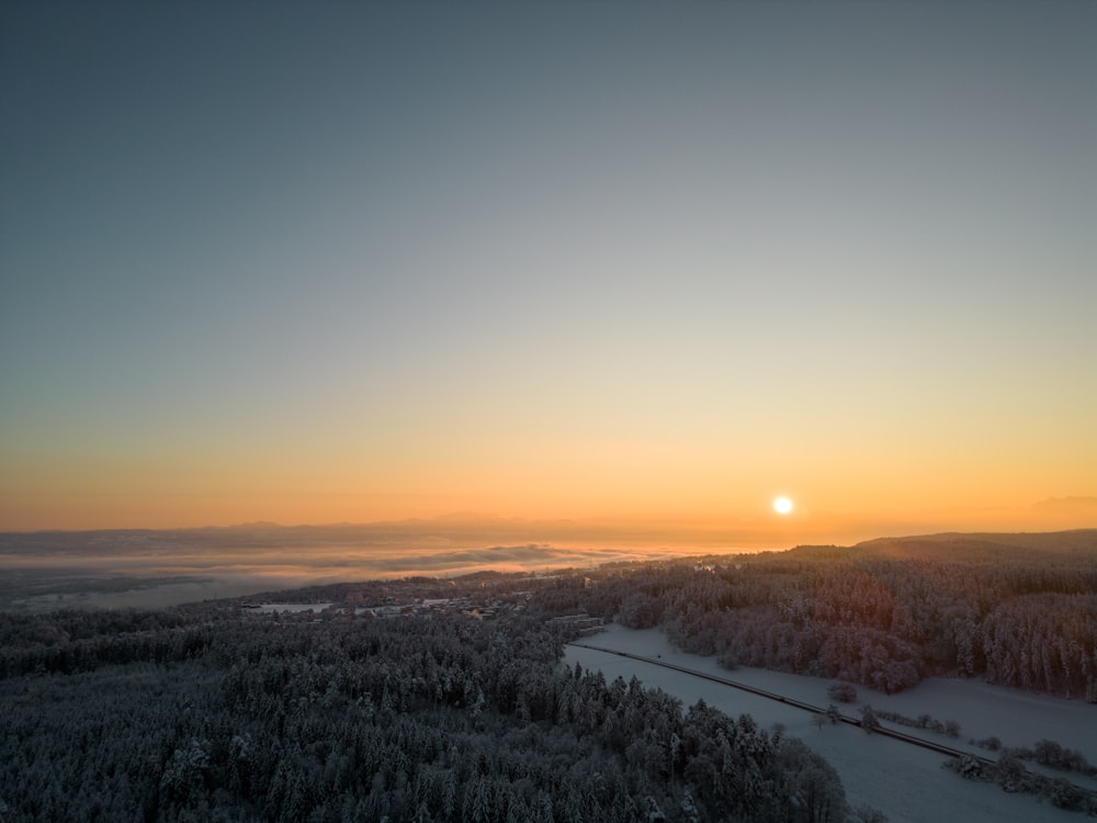 the sun is setting over a snowy landscape