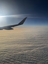 3D-rendered airplane soaring above cotton-candy clouds with soft shadows.