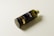 A sleek, dark-colored plastic bottle lying on its side, with the word 'mockup' prominently displayed on its label. The bottle has a cylindrical shape with a gold band near the bottom and a greenish cap on top.