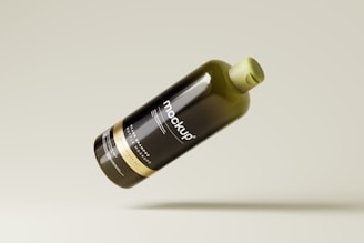 A sleek, dark glass bottle featuring labeled text indicating it is a mockup design. The bottle is tilted and floating against a neutral, light background.