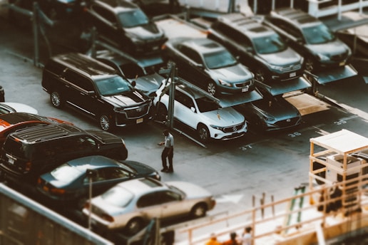 A valet attendant in uniform assisting a customer with their car at a busy corporate parking lot