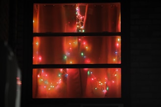 Colorful string lights draped around a festive mantel and window frame.