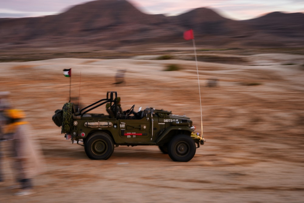 a jeep with a flag on top of it in the desert