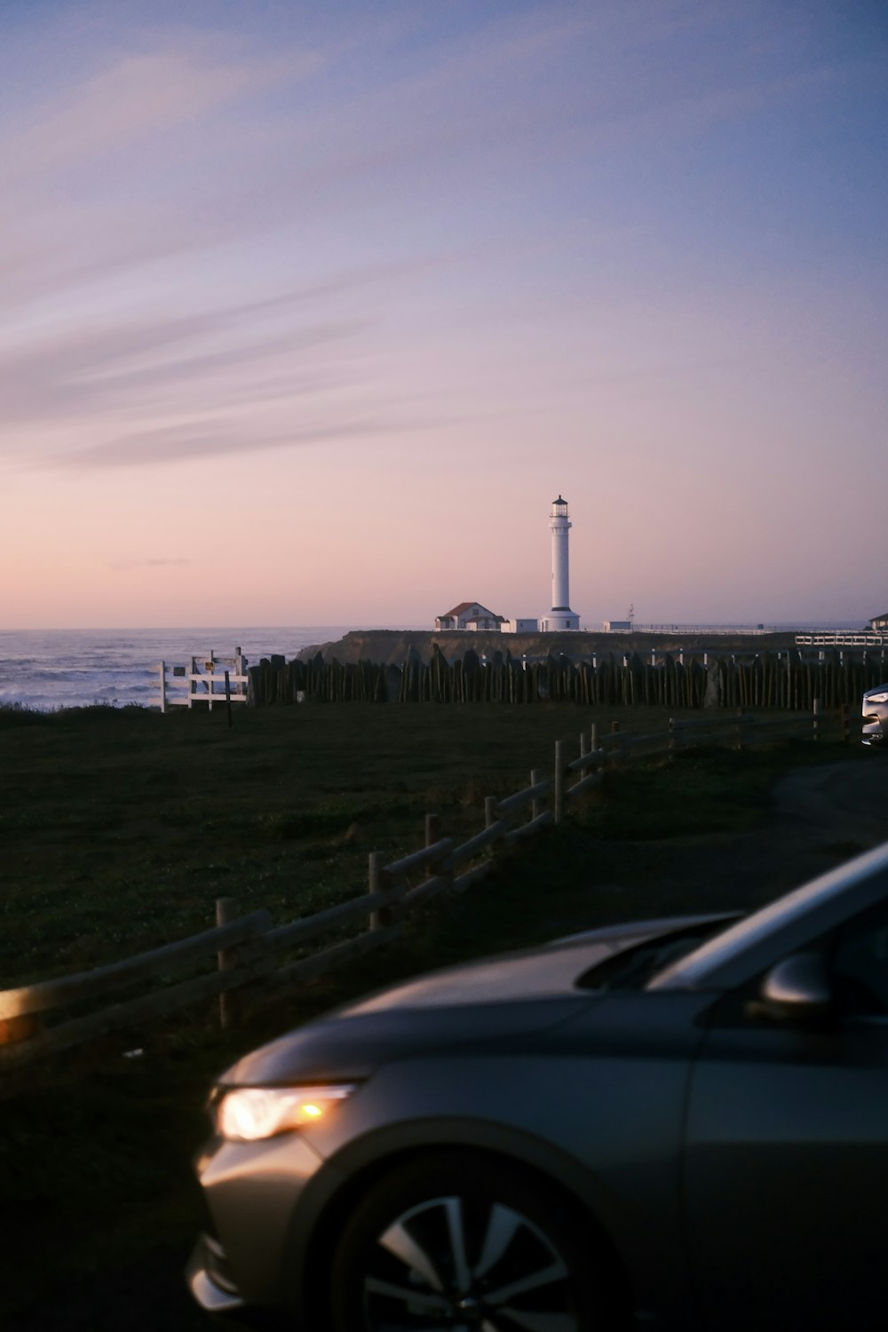 a car parked on the side of a road next to a light house