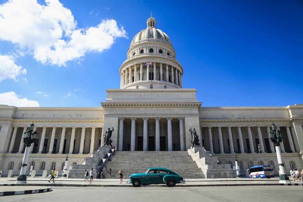 a green car parked in front of a large building