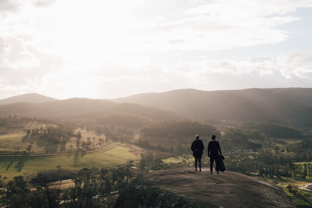 a couple of people standing on top of a hill