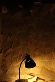 Dark, moody workspace with thriller manuscripts and a red lamp casting shadows.