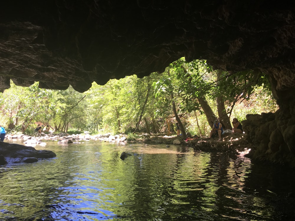 a person standing in the water under a cave