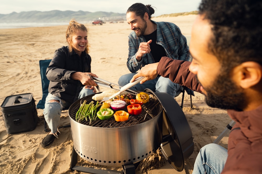 un uomo e una donna che cucinano sulla spiaggia