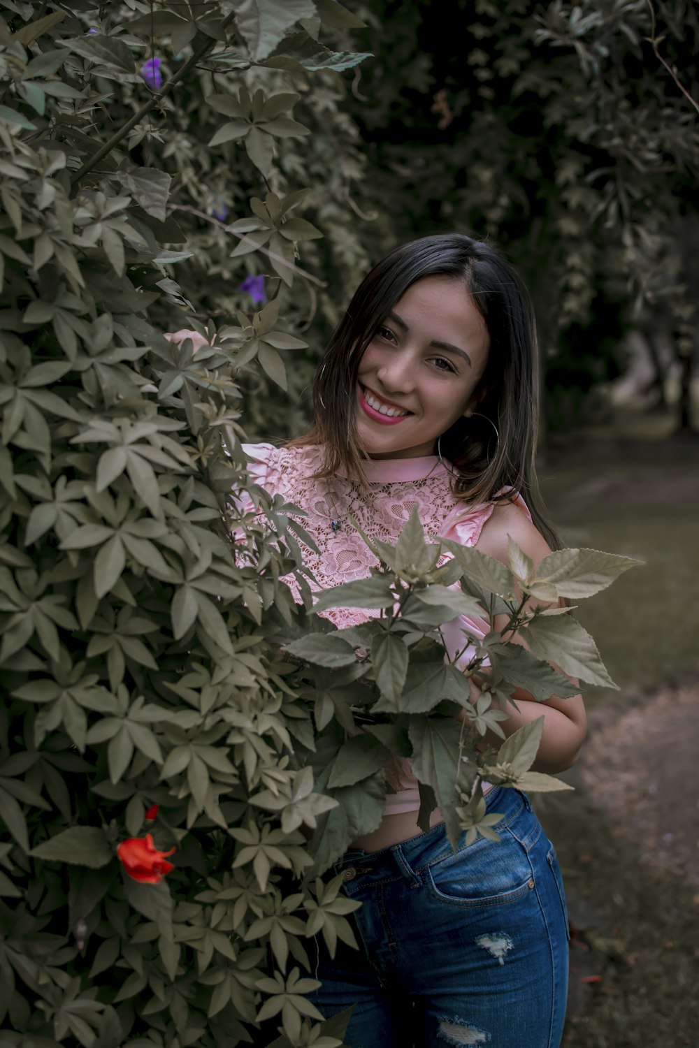 a young girl is posing for a picture in front of a bush