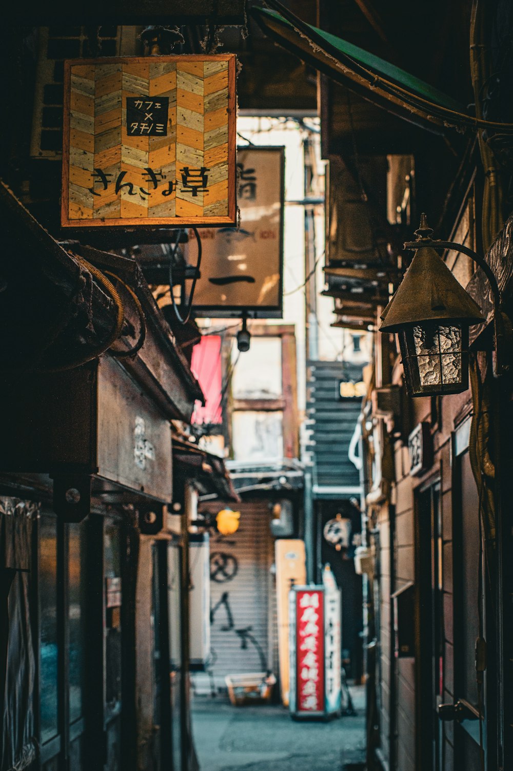 a narrow alley way with signs hanging from the ceiling