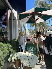 People warmly chatting around a small coffee stand during a sunny election day.