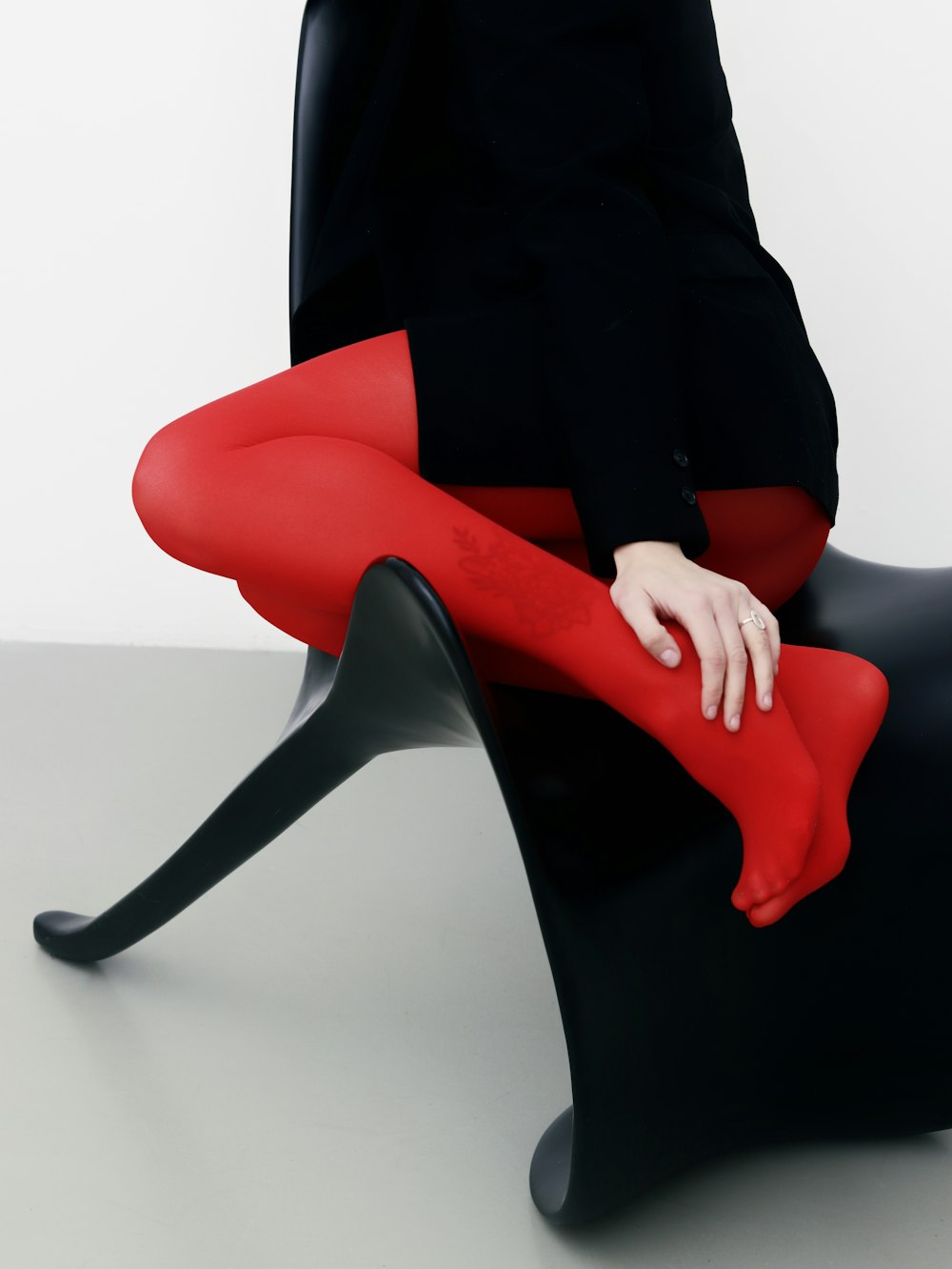a woman sitting on a black chair with red stockings