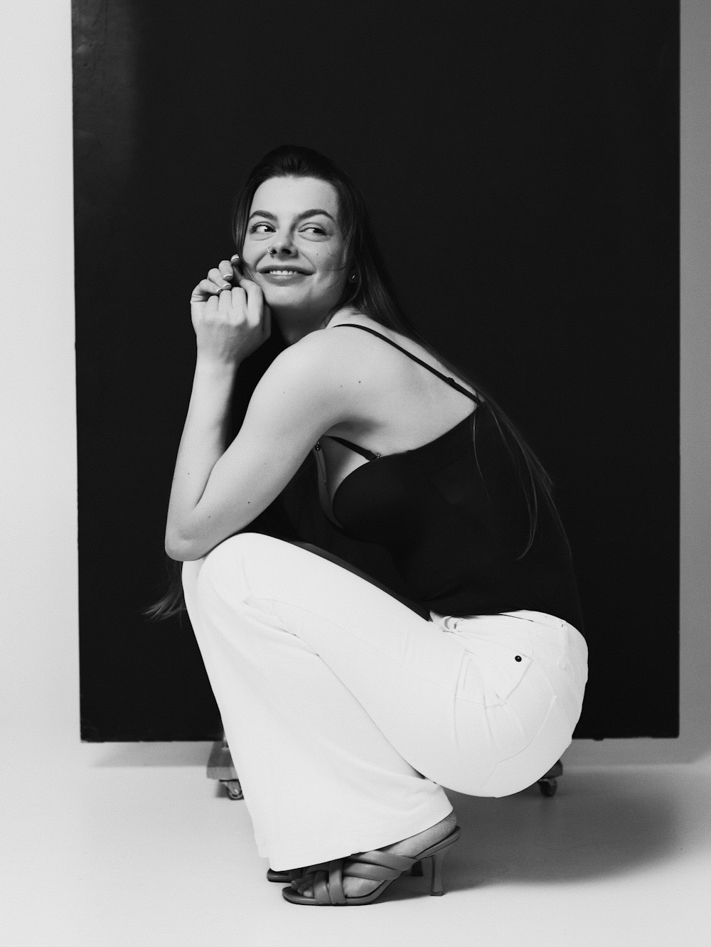 a black and white photo of a woman sitting on a skateboard