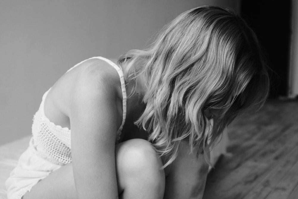 a black and white photo of a woman kneeling on a bed