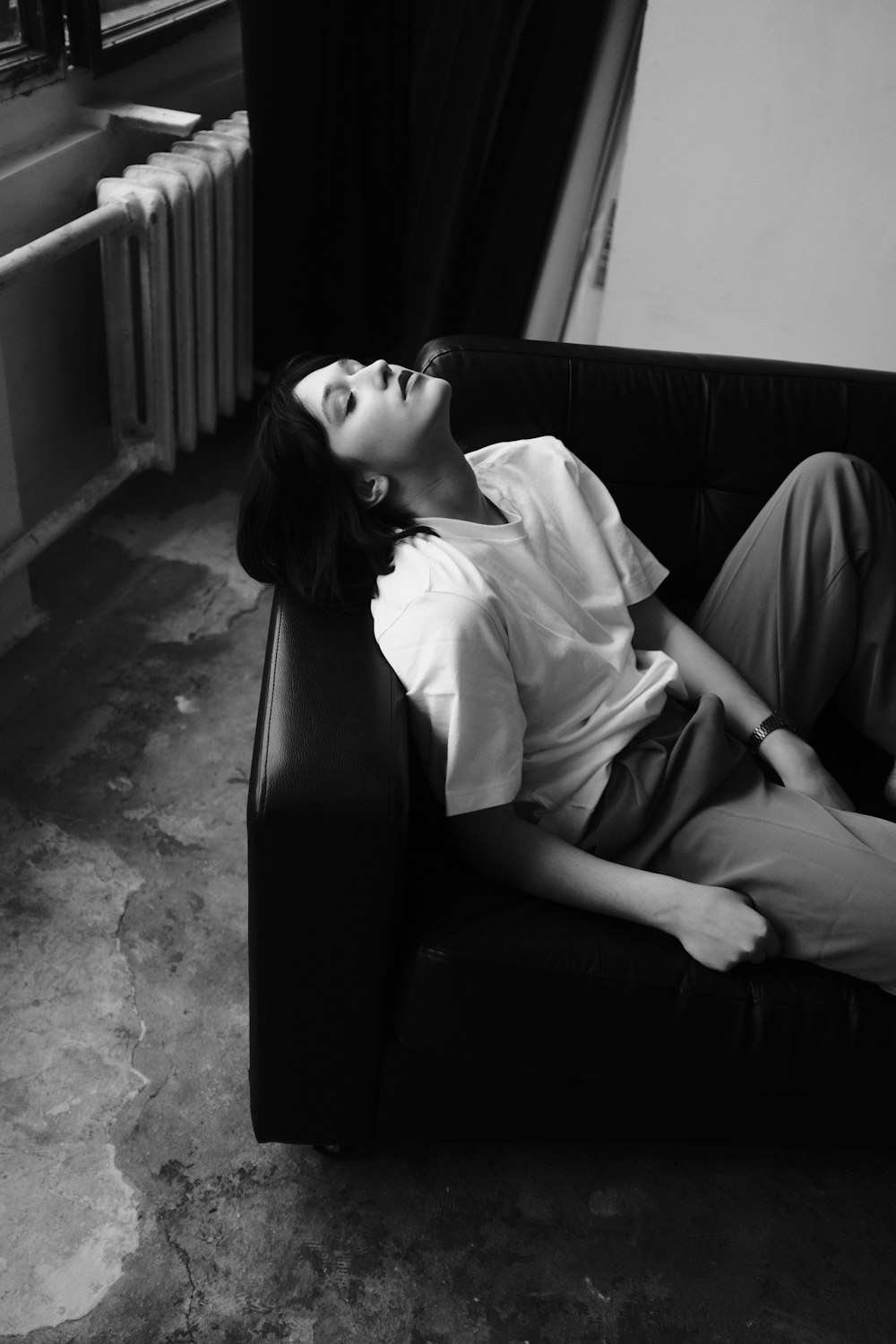 a woman laying on top of a couch next to a radiator