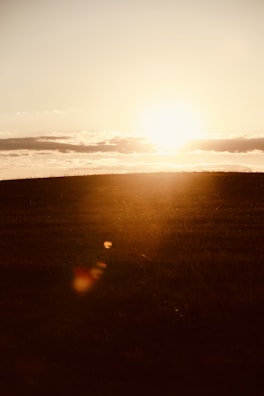 A serene landscape at sunset with soft golden light over rolling hills.
