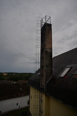 Technician in uniform inspecting a chimney on a sunny Melbourne rooftop.