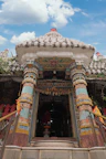Entrance of Geeta Bhawan Ashram featuring light blue and saffron accents under a clear sky.