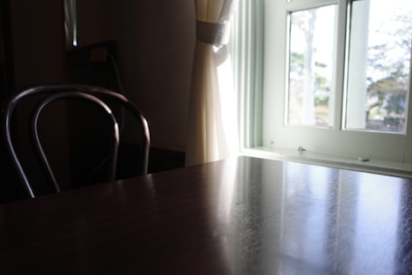 A professional cleaner gently wiping a wooden table using eco-friendly products in a sunlit living room.