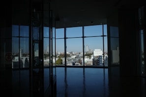 A spacious room featuring a large window with a view of the city.
