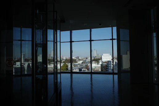 Interior view of a stylish 1 BHK apartment with floor-to-ceiling windows overlooking the Mumbai skyline at dusk.