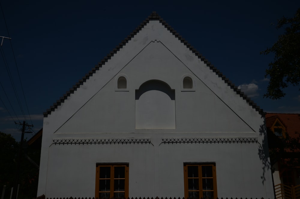 a white building with two windows and a roof