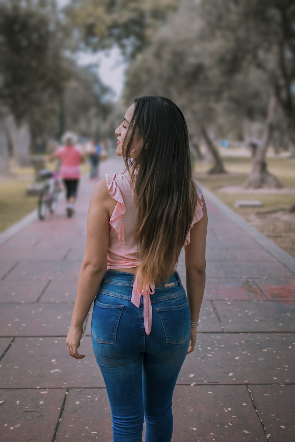 a woman walking down a sidewalk with her back to the camera