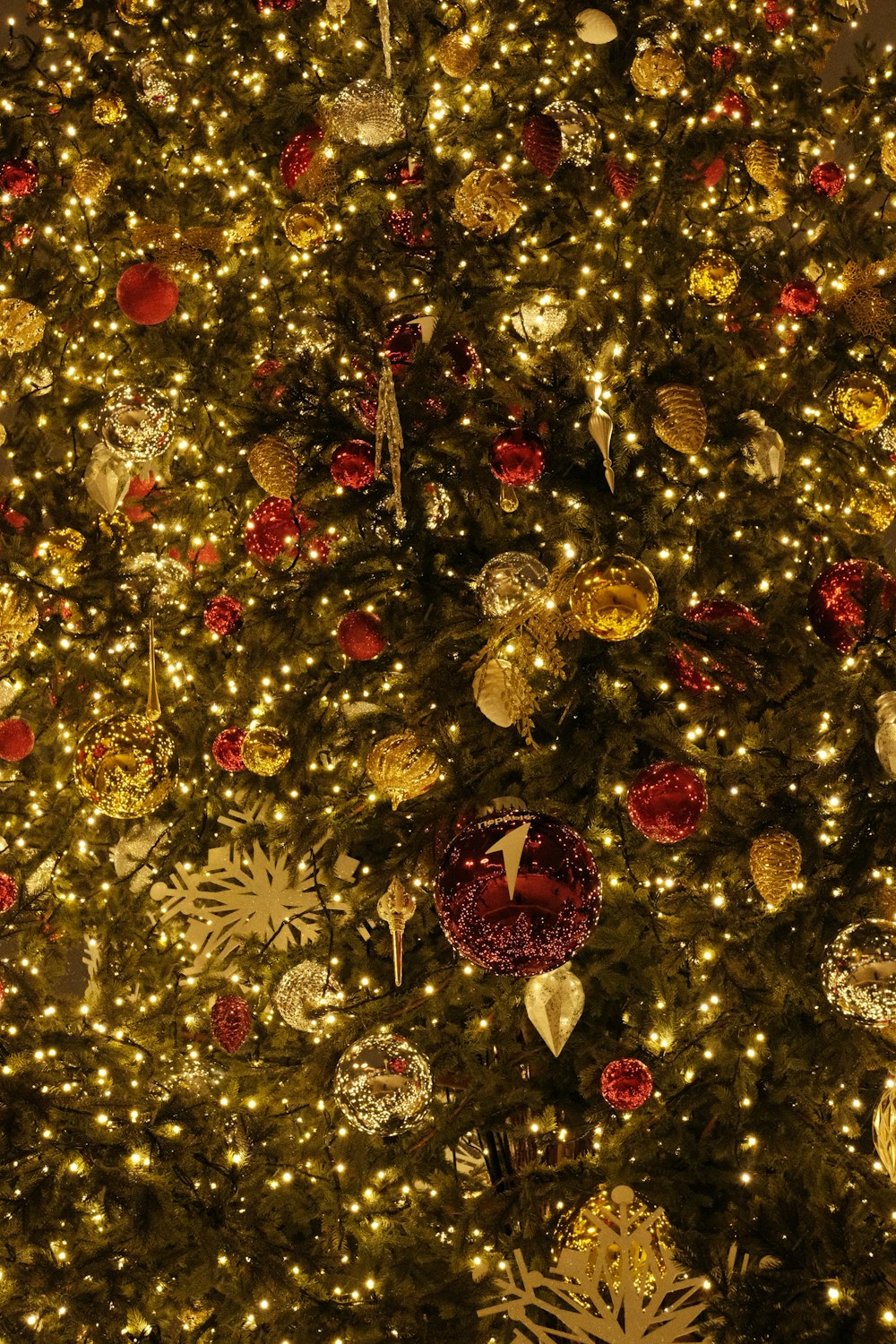 a large christmas tree is decorated with gold and red ornaments