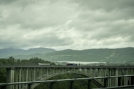 A d. dalto transportes truck crossing a scenic bridge with mountains in the background.