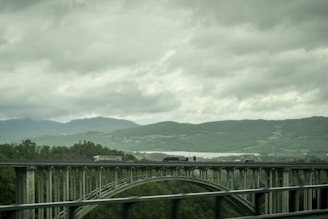 A d. dalto transportes truck crossing a scenic bridge with mountains in the background.