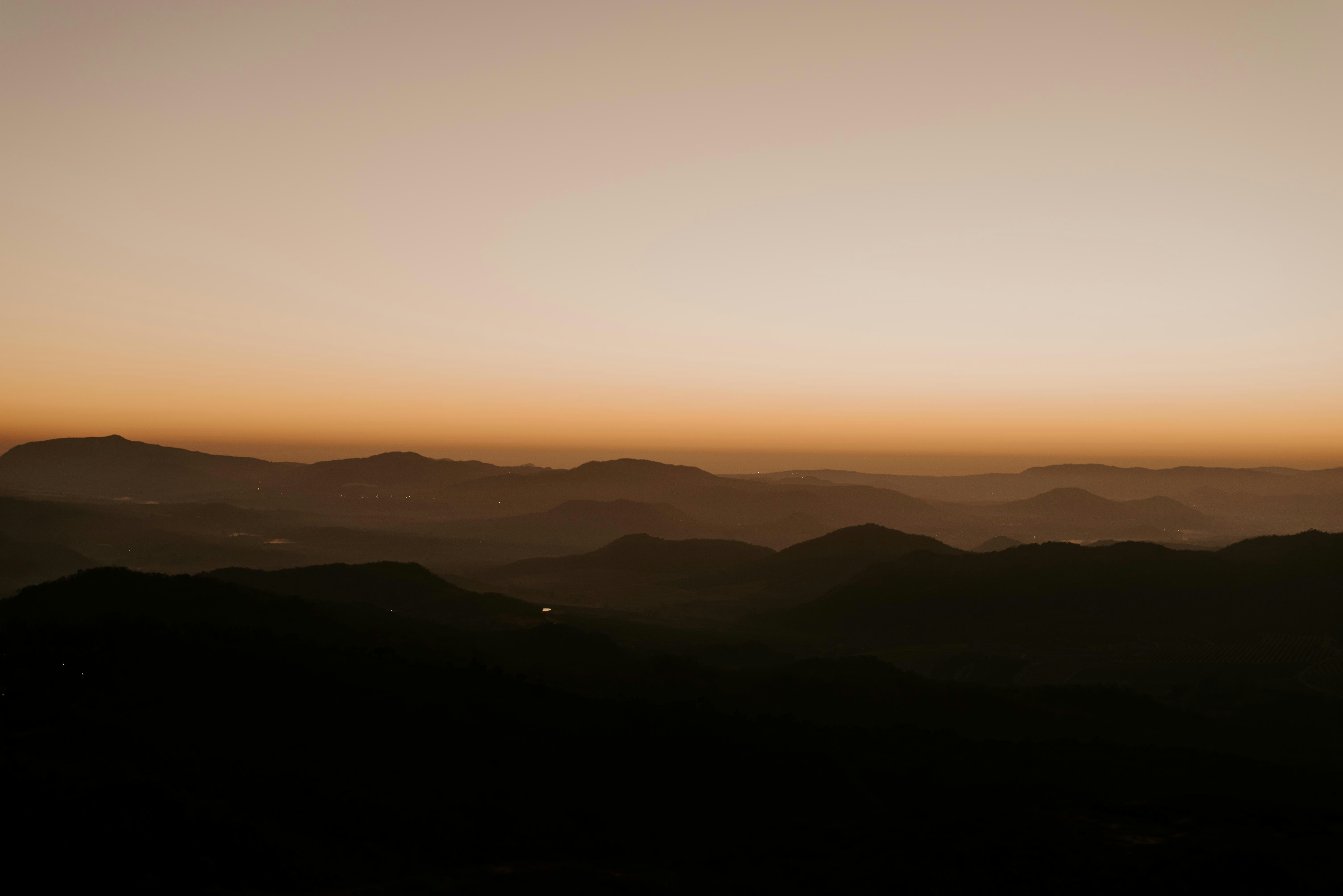 the sun is setting over a mountain rangeby Carmen Comrie