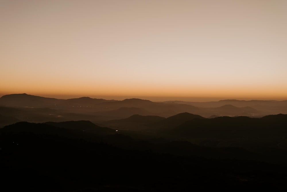 the sun is setting over a mountain range