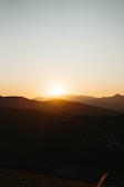 A serene landscape painting featuring a sunset over hills.