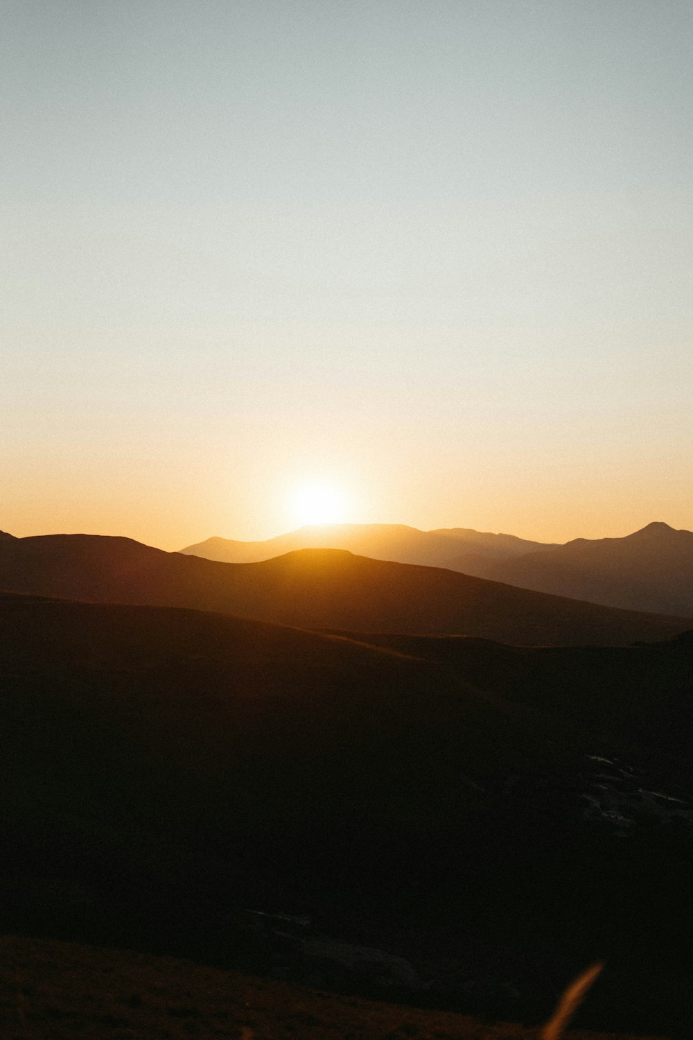 the sun is setting over a mountain range