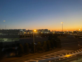 A wide angle view of a commercial parking lot with newly applied straight, reflective blue and white lines under twilight lighting.
