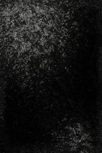 A dark image with scattered small points of light that resemble stars or distant galaxies in a night sky. The light is concentrated in clusters, with one large area at the top and a smaller cluster near the bottom. The surrounding area is mostly dark, enhancing the contrast with the bright points.