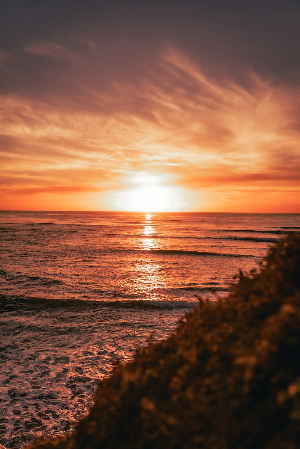 the sun is setting over the ocean on a cloudy day