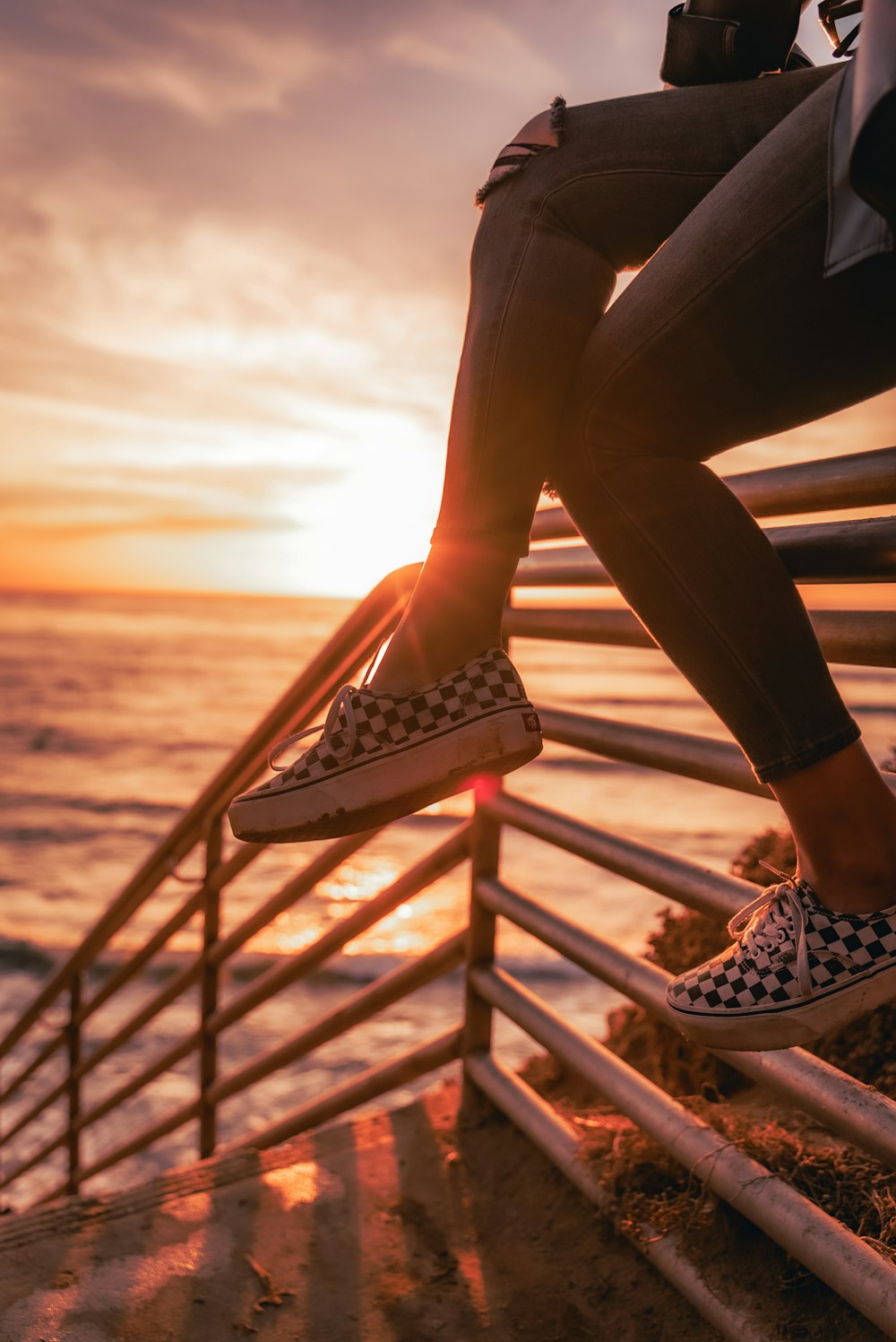 a person sitting on a railing near the ocean