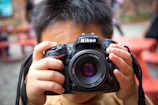 Close-up of a smiling child holding a camera, ready for their school photo.
