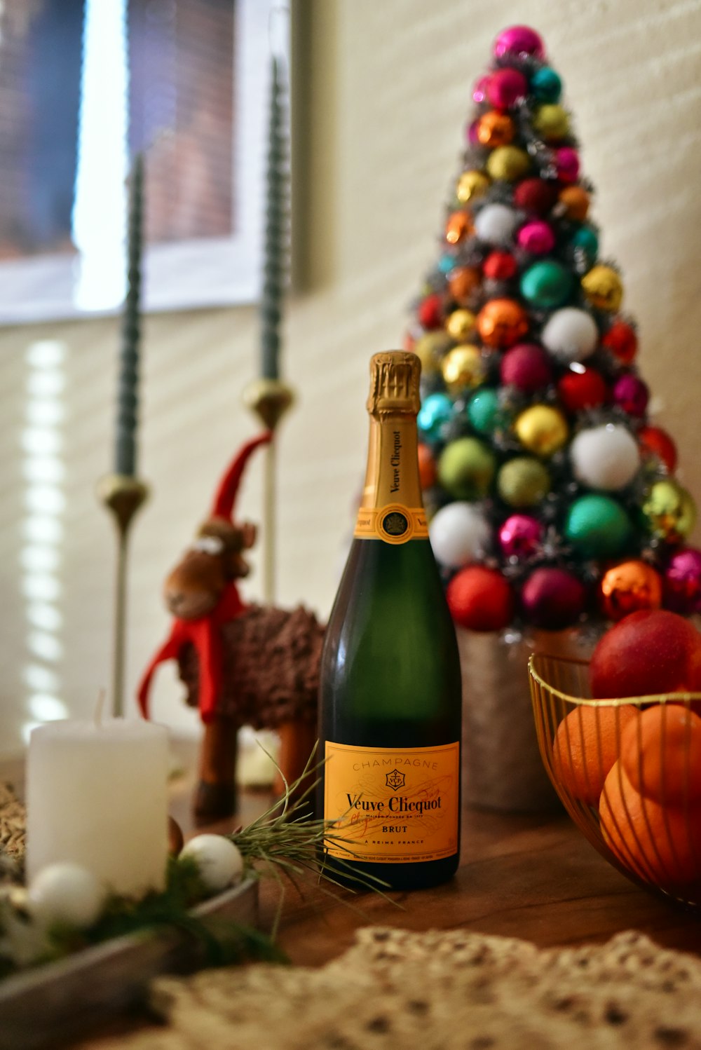 a bottle of champagne sitting next to a christmas tree