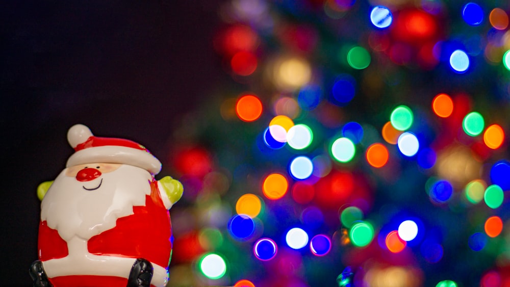 a santa clause figurine sitting in front of a christmas tree