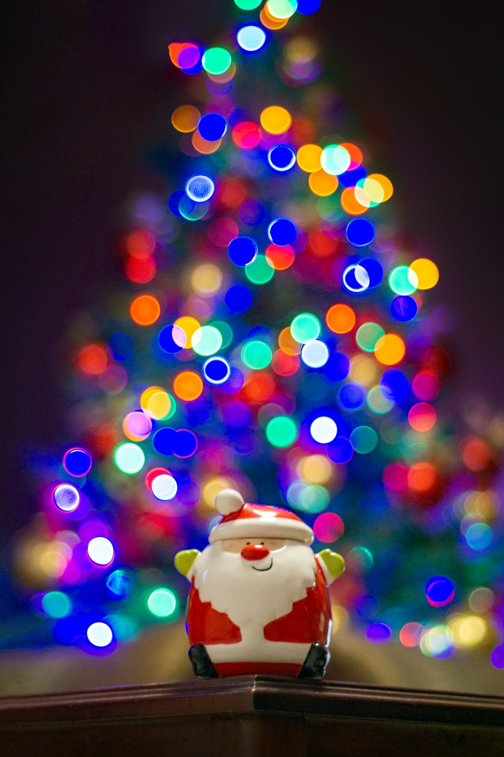 a santa clause figurine sitting in front of a christmas tree