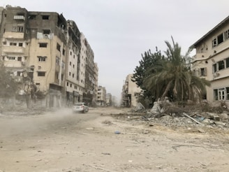 a car driving down a dirt road next to tall buildings